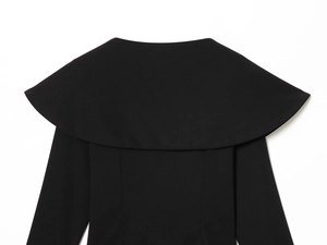 Detail of elegant black long sleeve top featuring a wide cape collar and structured fabric