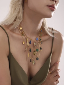 Gros plan sur un collier doré multi-rangs avec pendentifs poisson, cœur et émail coloré