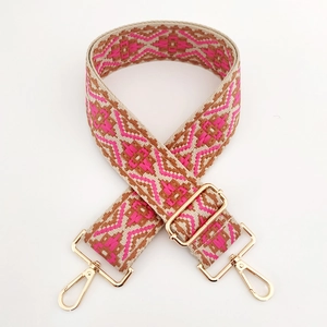 Close-up of geometric ethnic woven bag strap with golden metal swivel hooks and buckles
