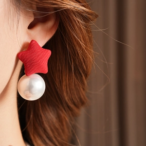 Close-up of a model wearing red fabric star earrings with large white imitation pearls