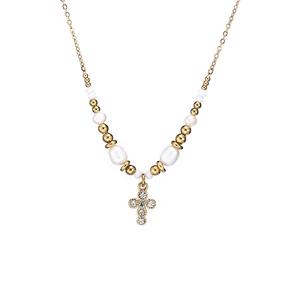 Macro detail of gold plated cross pendant with rhinestones and white pearls jewelry set