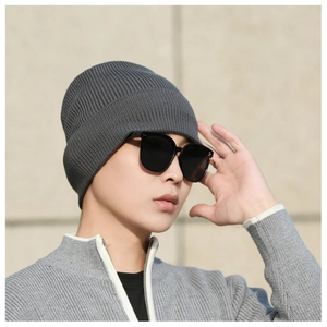 Detailed view of dark grey ribbed knit beanie worn by model in outdoor setting