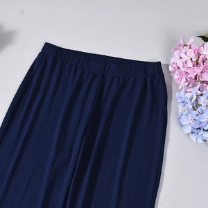 Detail view of dark blue knitted high waist trousers displayed with floral accents