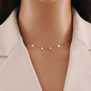 Close-up of gold geometric square pendant necklace paired with a white blazer for women