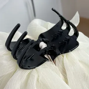Macro detail of large black hair claw clip with layered white chiffon bow decoration