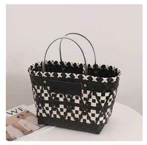 Detail of black and white woven basket bag featuring circular handles and wavy trim