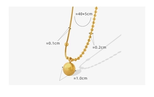 Vue détaillée du collier double chaîne doré avec pendentif pièce Lucky et maille serpent