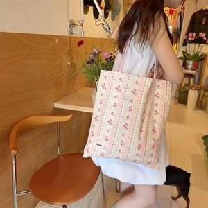 Détail de vue latérale du sac fourre-tout en toile blanc cassé avec motifs de fleurs roses