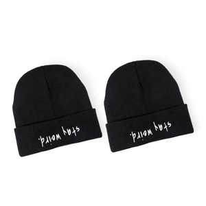 Classic black knitted beanie with white 'stay weird' embroidery in a minimalist style