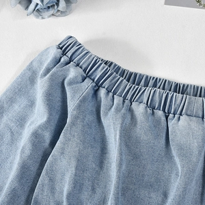 Detailed macro view of the elastic waistband on a light blue denim romper suit