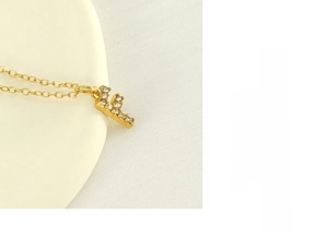 Detailed macro view of a gold stainless steel letter F pendant with small zircon stones