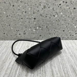 Detailed view of black woven genuine leather handbag with knot strap on stone surface
