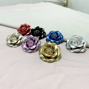 Close-up of vintage metallic camellia pins in multi-color finishes on soft fabric