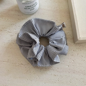Detailed view of large navy striped scrunchie with branded woven label on a textured surface