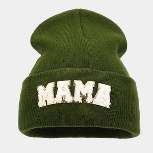 Close-up of olive green knit beanie featuring MAMA embroidered patch with gold trim