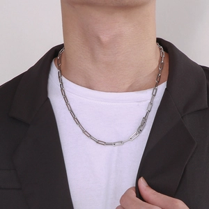 Close-up of a silver stainless steel rectangular link chain worn by a male model