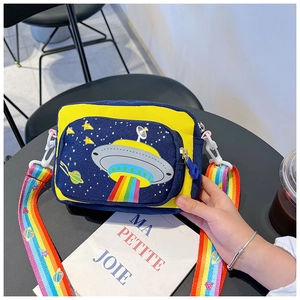 Close-up of a space-themed blue kids crossbody bag with rainbow strap on a black table