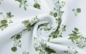 Primer plano de tela de algodón blanca suave con estampado floral verde y textura