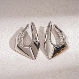 Detailed close-up of silver geometric abstract stud earrings with a hollow 3D design