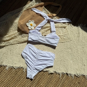 Dettaglio flat lay di un bikini bianco a vita alta con texture increspata su una stuoia