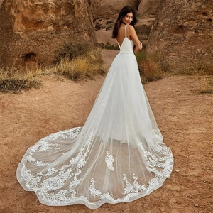 Robe de mariée sexy col V dos nu avec longue traîne en dentelle devant un décor de désert