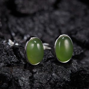 Close-up of S925 sterling silver oval jasper stud earrings on a dark charcoal surface