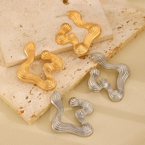 Detailed close-up of chunky irregular wavy metal earrings in polished gold and silver finishes