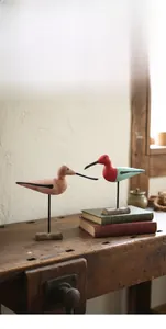 Detail of hand-painted wooden bird statues with rustic finish on black metal stands