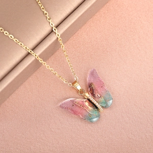 Macro shot of gradient butterfly pendant with gold foil and crystals on a delicate chain