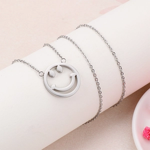 Gros plan détaillé d'un pendentif smiley argenté sur une fine chaîne à maillons