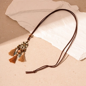 Detail of vintage bohemian long sweater necklace with bronze floral pendant and tassels