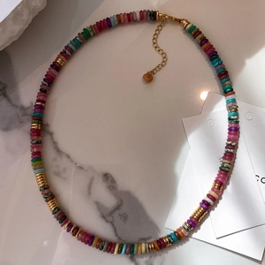 Macro shot of colorful natural stone disc beads and golden threaded metal spacers on necklace