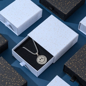 Dettaglio della collana con ciondolo smiley argento in scatola regalo bianca e oro a cassetti