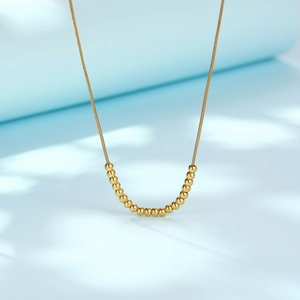 Minimalist gold beaded snake chain necklace for women on light blue background