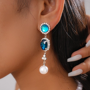 Close-up of vintage drop earrings with blue gemstones, pearls and sparkling rhinestones