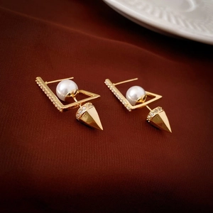 Detailed close-up of gold-plated geometric heart earrings with pearls and micro-pave spikes