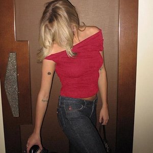 Detail of red off-shoulder slim fit top with ruched texture on a model wearing denim
