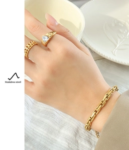 Detail of gold chunky chain bracelet and heart stone ring in polished stainless steel