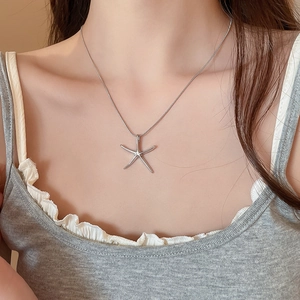 Close-up of a silver starfish pendant necklace on a woman's neck for beach vacation