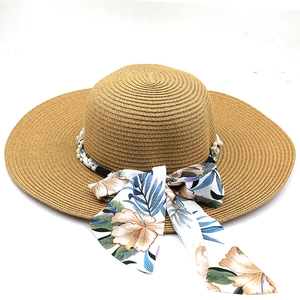 Detail of bohemian straw sun hat with floral silk scarf bow and elegant pearl trim