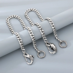 Detail view of steel trouser chains featuring intricate dragon and eagle head clasps