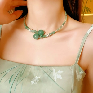 Dettaglio di una collana di perle di giada verde con tocchi argentati su modella