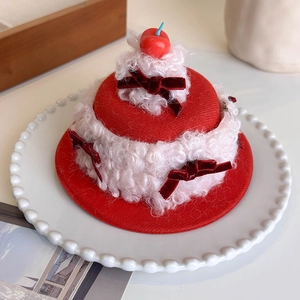Close-up of a cherry cake hair clip with red velvet bows and soft fleece texture