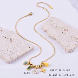 Detail of gold snake chain necklace with colorful heart and flower charms on stone props