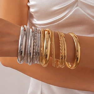 Close-up of stacked gold and silver textured geometric metal bangles on a model's arm