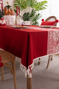 Detail of red Christmas tablecloth with snowflake pattern, jacquard fabric and white tassels
