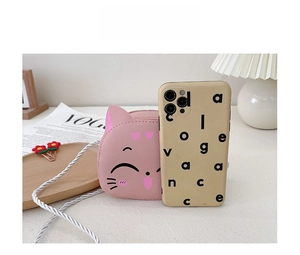 Pink cartoon cat PU crossbody bag size comparison with a smartphone on a desk