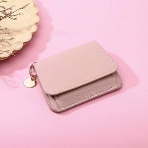 Pink leather wallet detail showing lychee texture and a gold round pendant tag