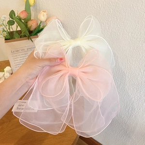 Close-up of oversized white and pink organza bow hair clips with elegant texture
