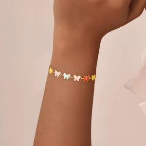 Detailed macro view of gold chain bracelet with colorful enamel butterfly charms